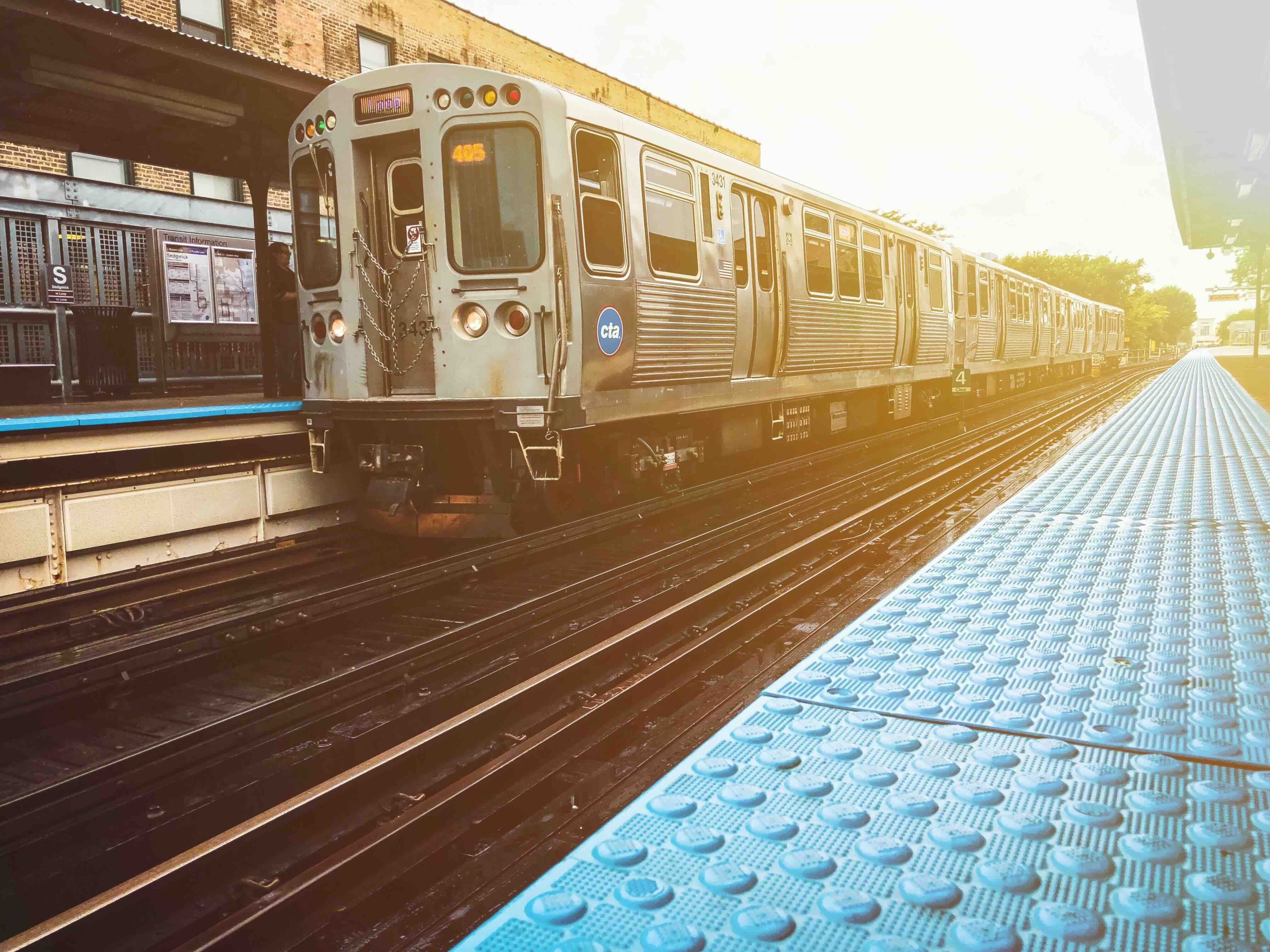 A photo of a CTA Brown Line train at the Sedgwick station with bright sun glow.